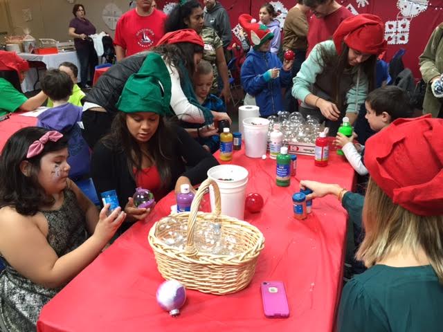 Miranda DOleo helps a party goer decorate a Christmas ornament at the annual Interact Pathways Christmas party
