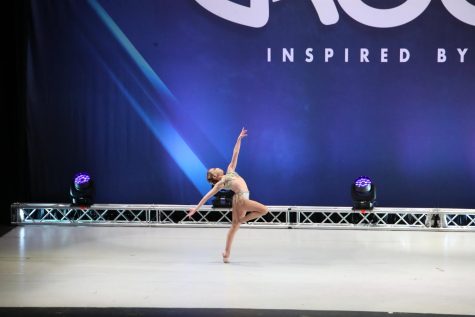 Caitlyn Muniz leaps across the stage at a competition