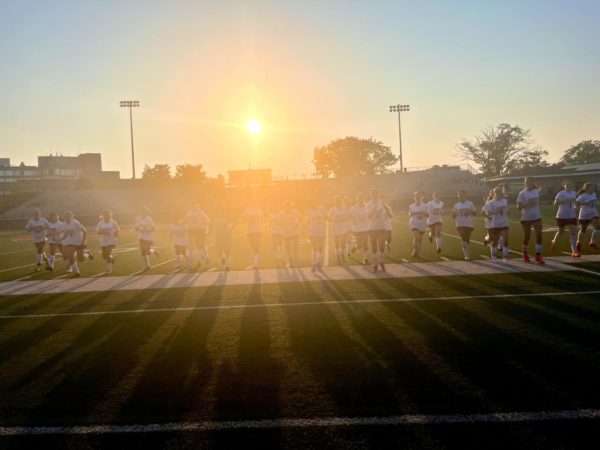 Girls soccer team takes a victory lap against the setting sun.