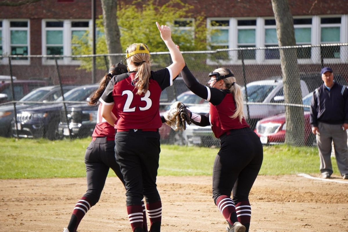 Cam Carroll (center) high fives teammates Ava Paone (back) and Lily Aiello (right)