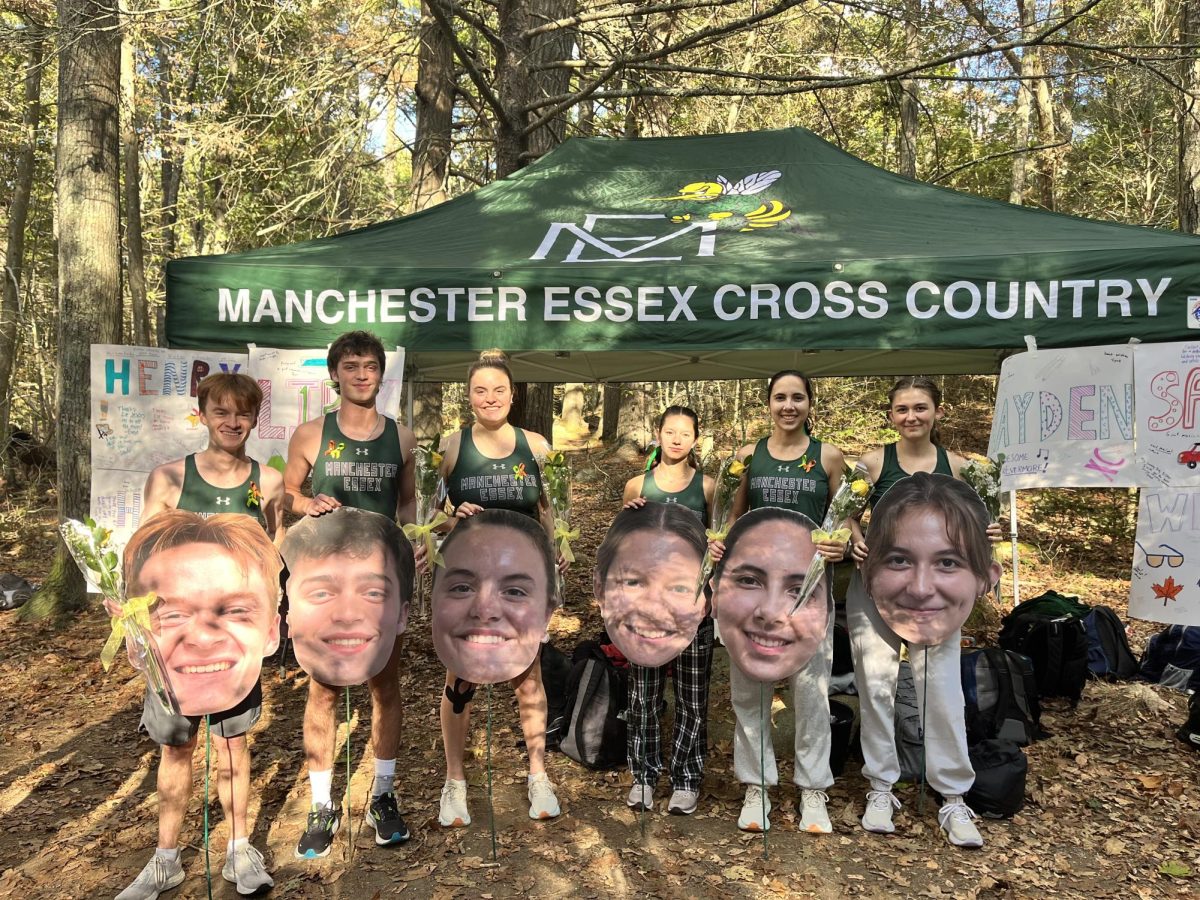 The Manchester-Essex Cross-Country seniors pose with flowers and their big-heads on their Senior Day.