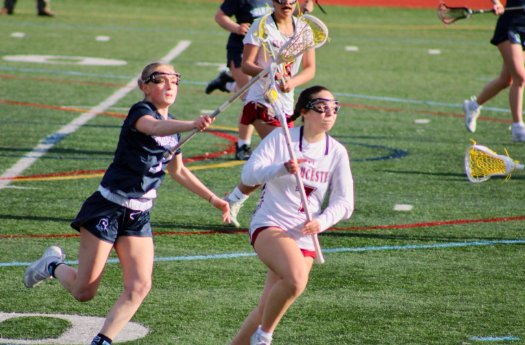 Sophia Ferrara runs downfield towards the net while being challenged by a defender.