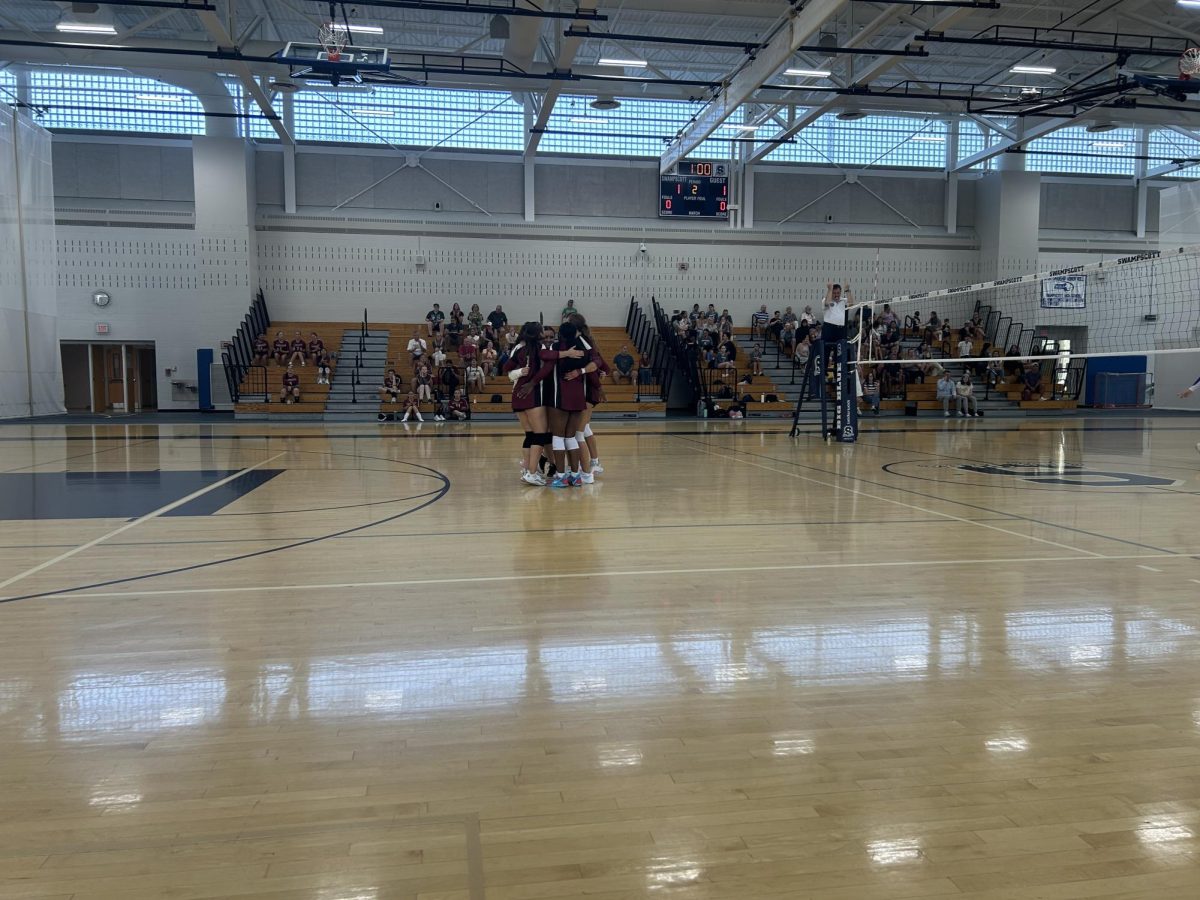 The girls' volleyball team huddles before a set in their game against the Big Blue.