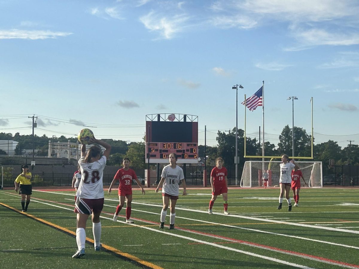 Gloucester soccer players stand on the pitch during their game.